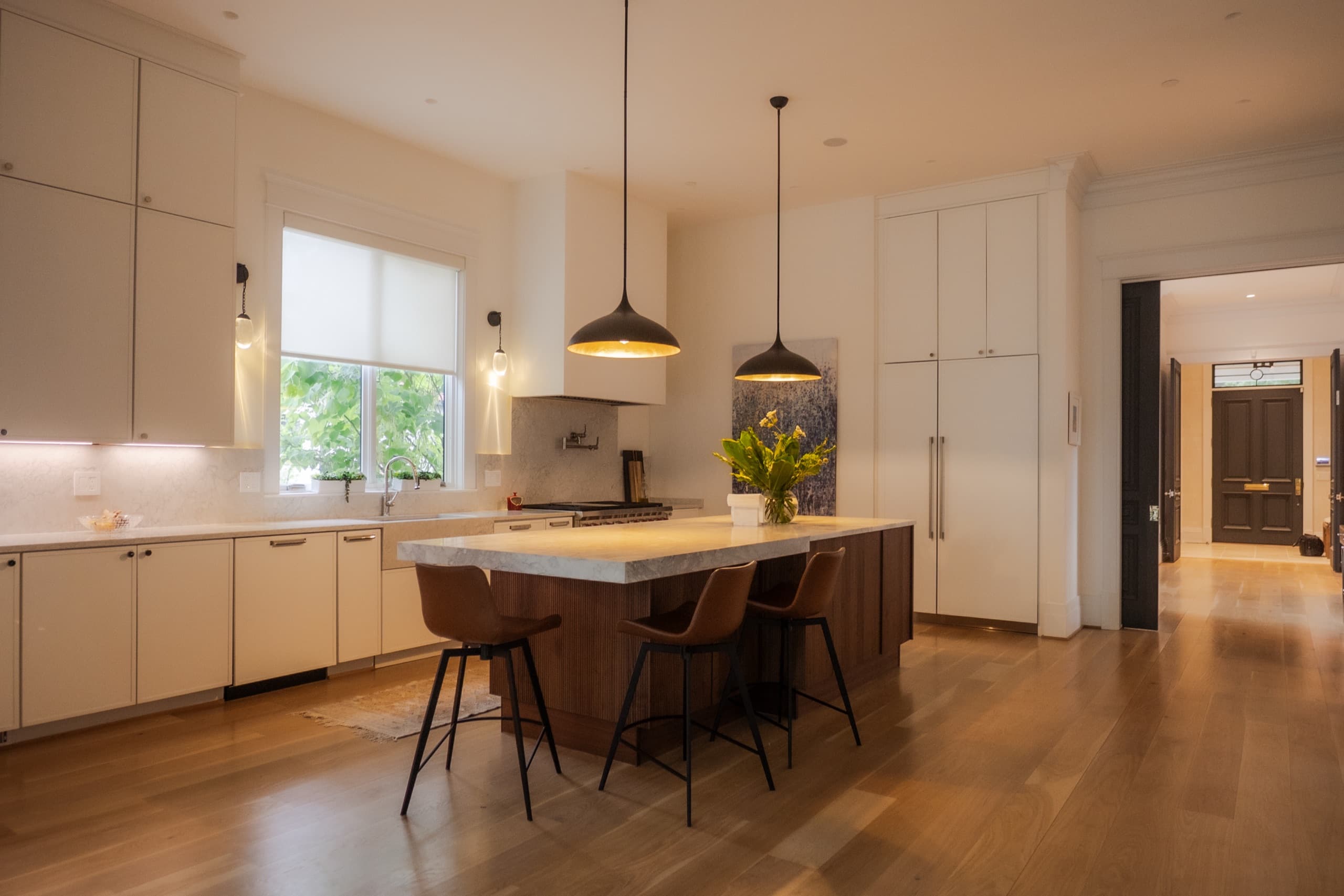 Kitchen with a walnut island, marble worktop and black dome pendant lights