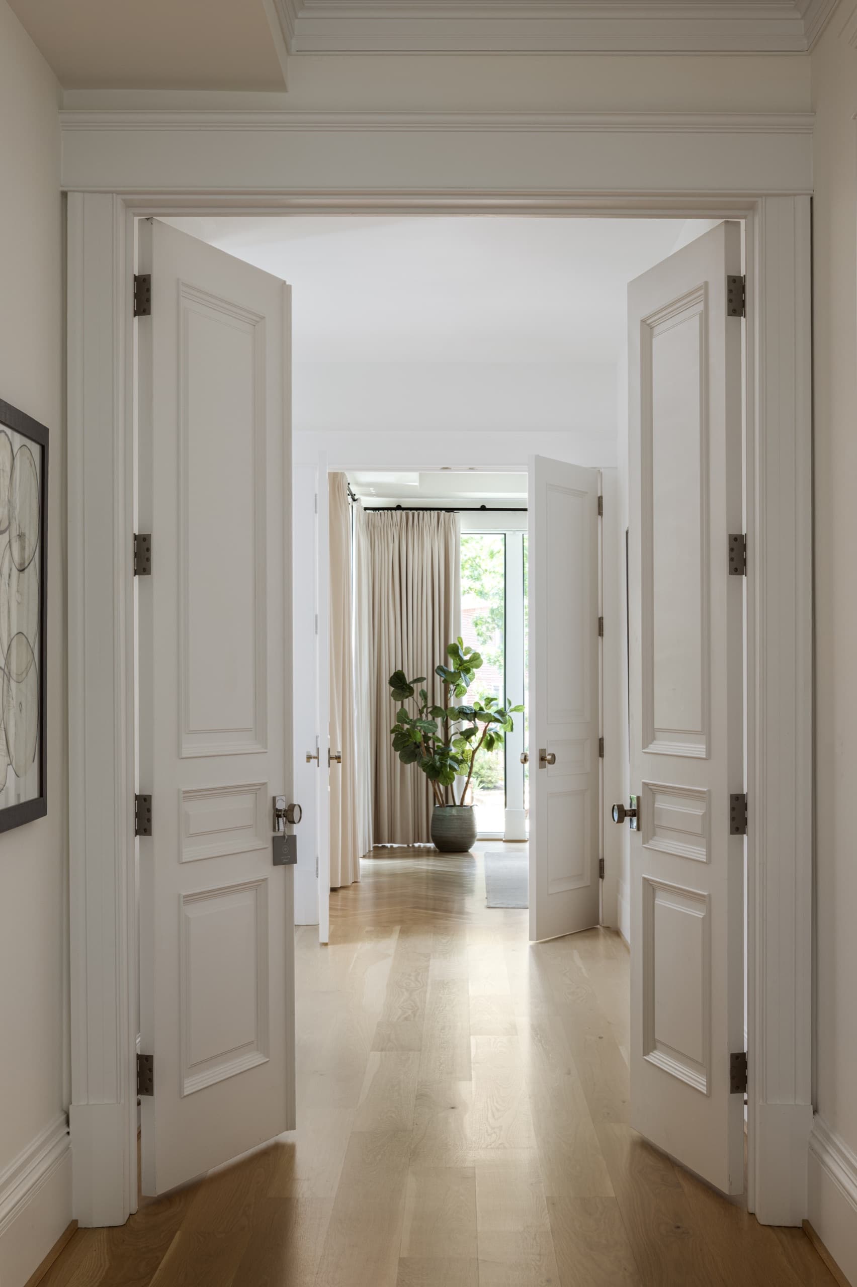 Enfilade of panelled double doors framing a view through the house to the garden