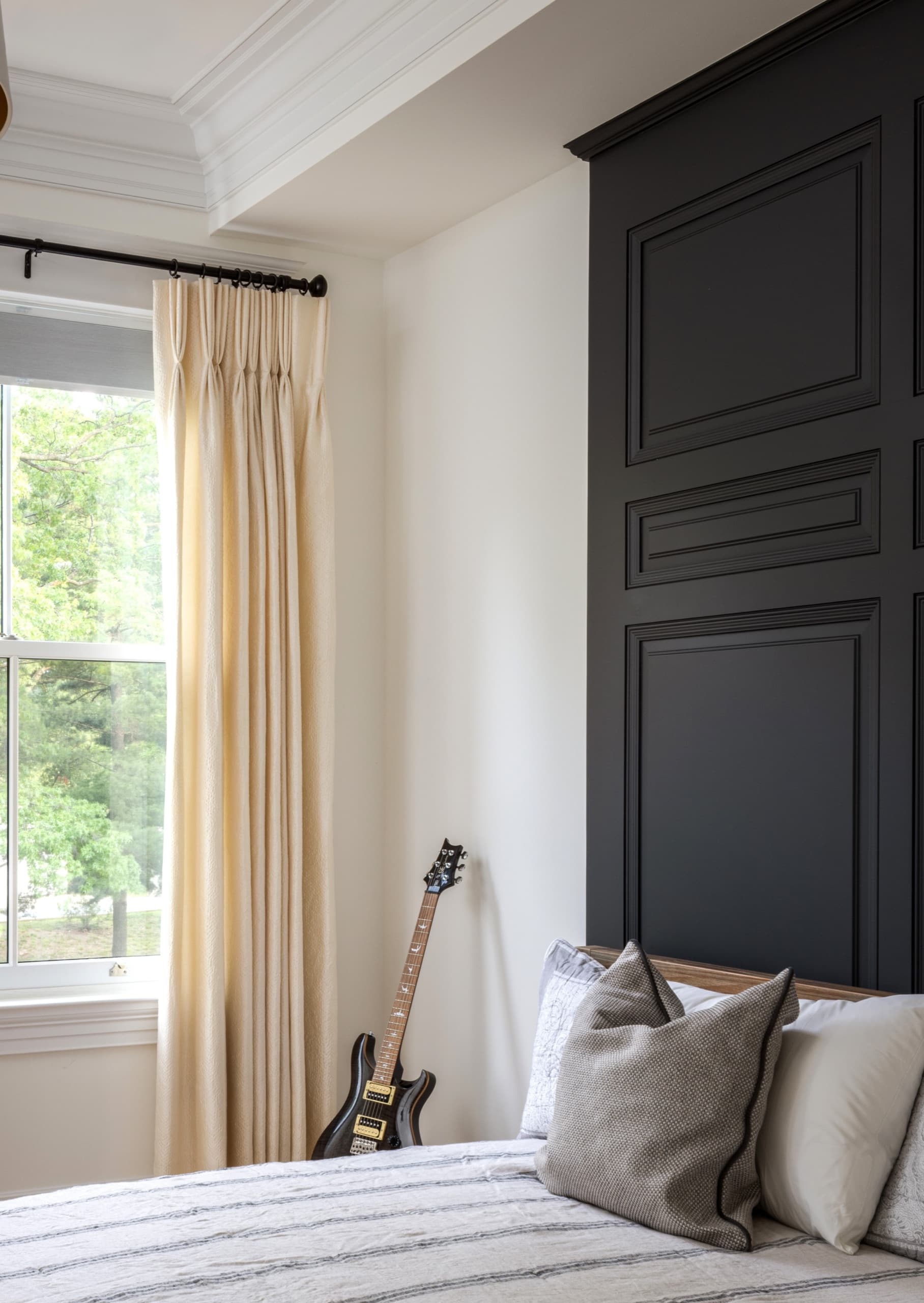 Bedroom with a black panelled feature wall and full-length linen curtains