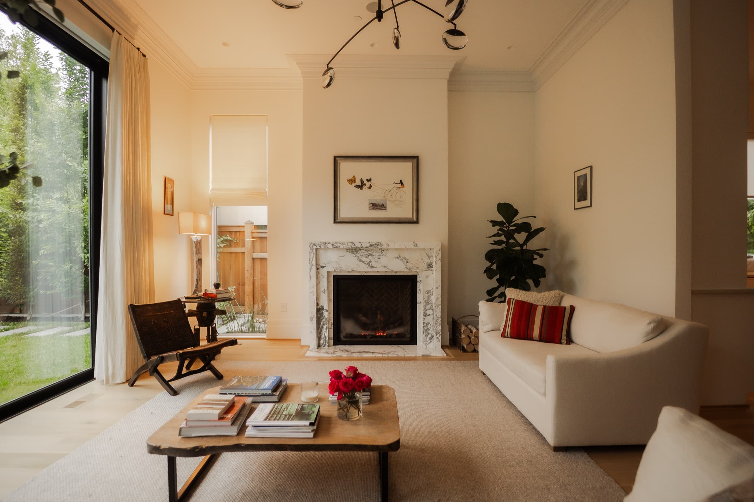 Double-height living room with a marble fireplace and a modern branched chandelier